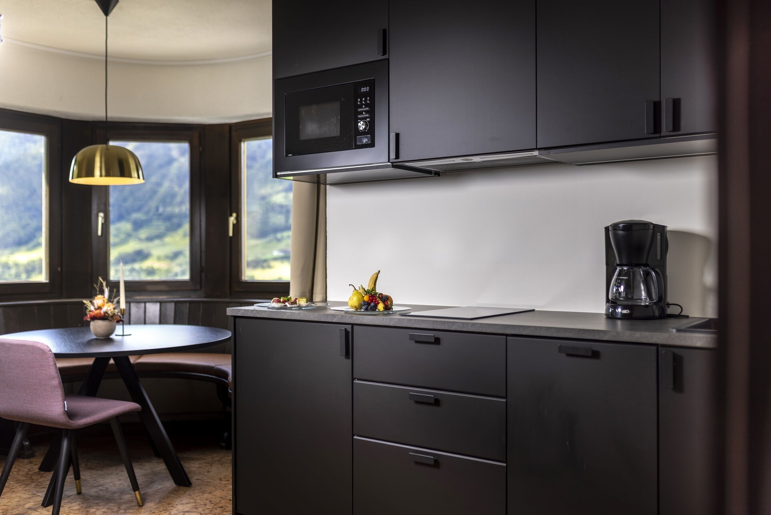 Una cocina moderna con microondas, cafetera y comedor con mesa y sillas.