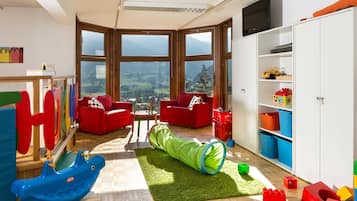 Children can play and explore amidst breathtaking mountain views through large windows.