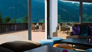 A terrace with outdoor seating, a glass partition, and a mountain view. - Hotel Goldried (Matrei in Osttirol)
