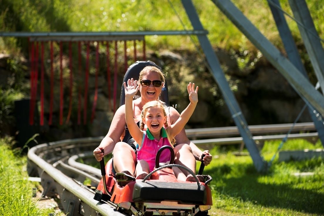 A roller coaster with two passengers, one adult and one child, enjoying the ride.