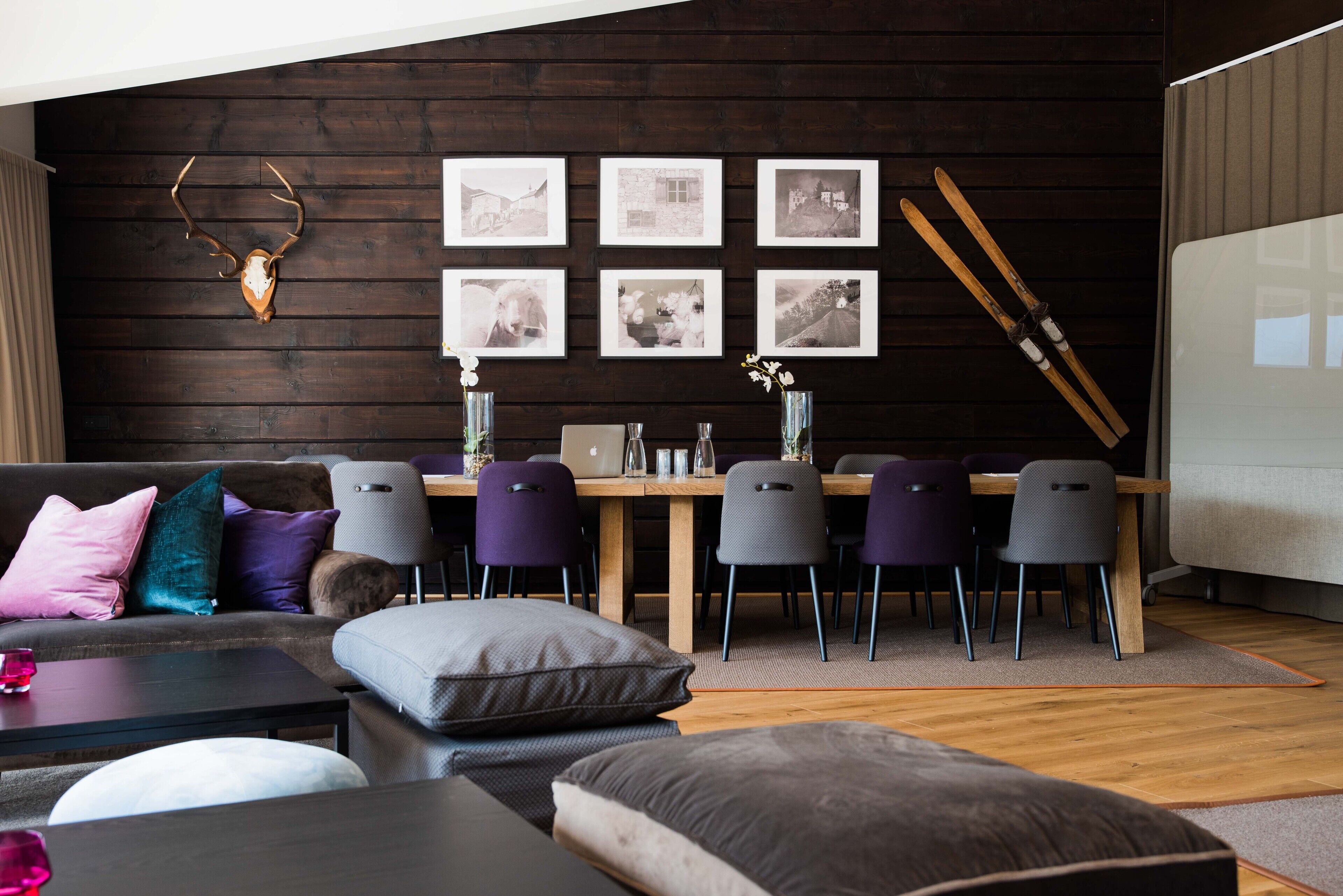 Una sala de estar moderna con una pared de madera oscura, una cabeza de ciervo montada, y un comedor con una mesa y sillas de madera.