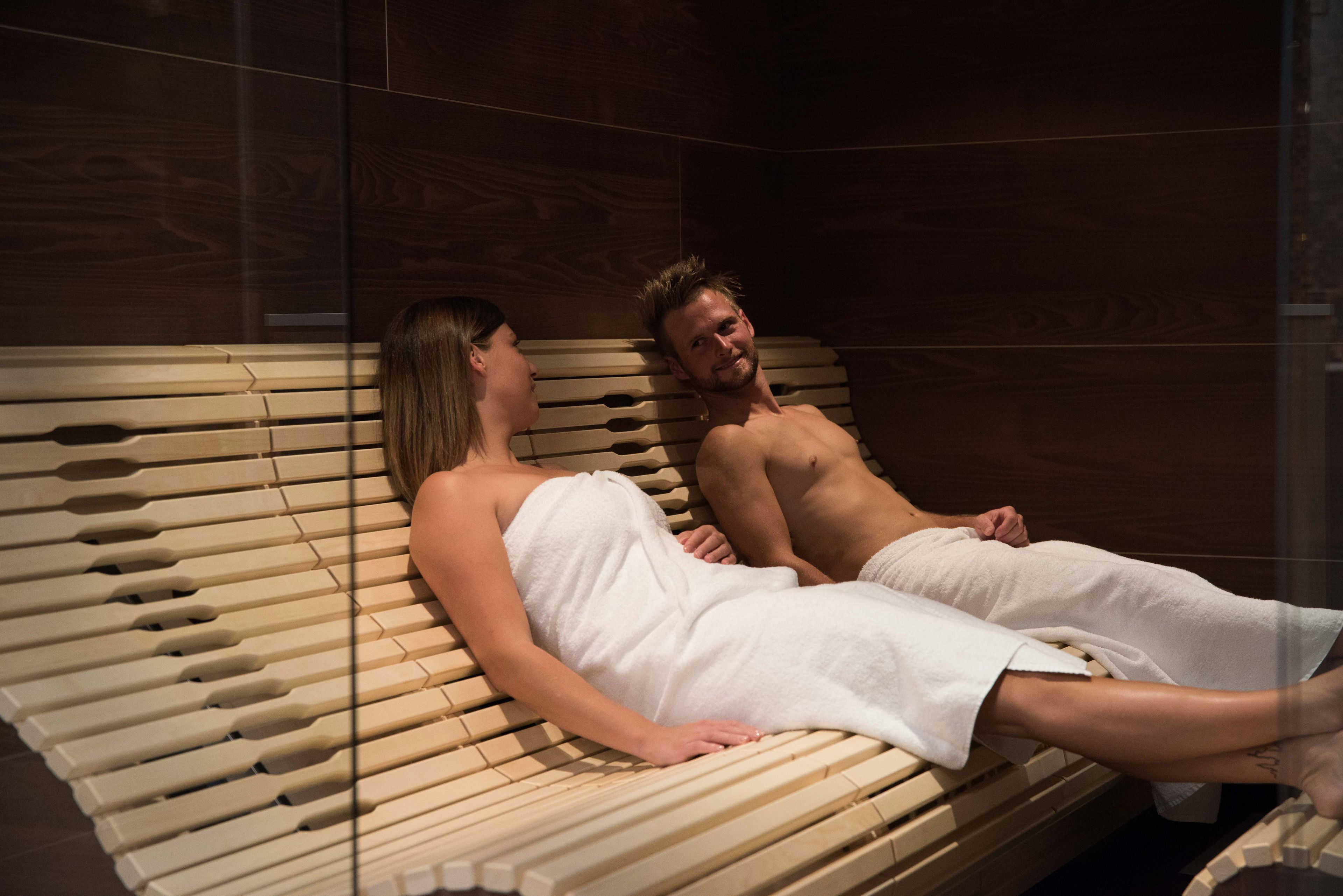 A wooden massage table with a person lying on it, covered with a white towel.