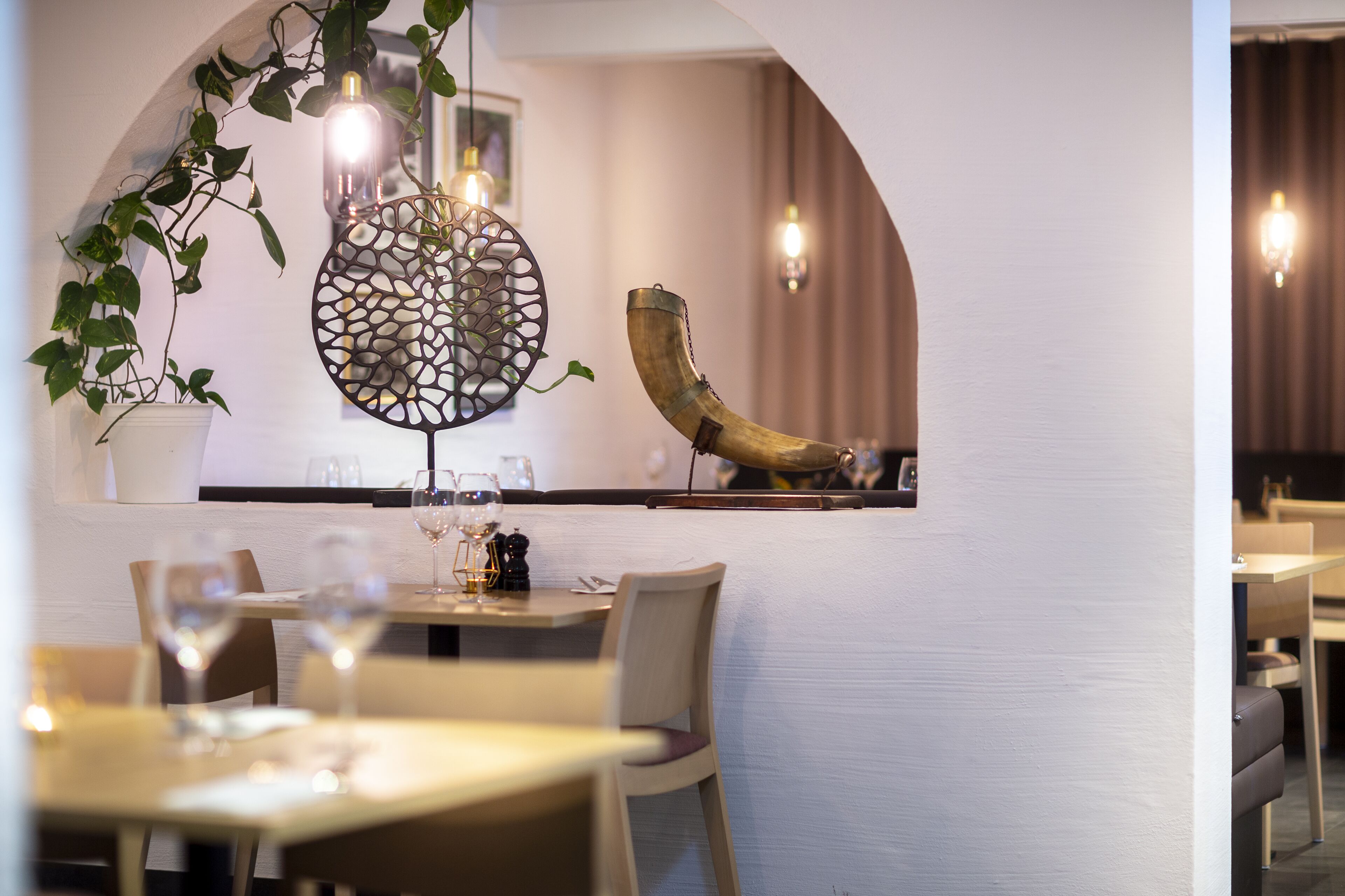 A restaurant interior with a dining area, tables, chairs, and hanging light fixtures.