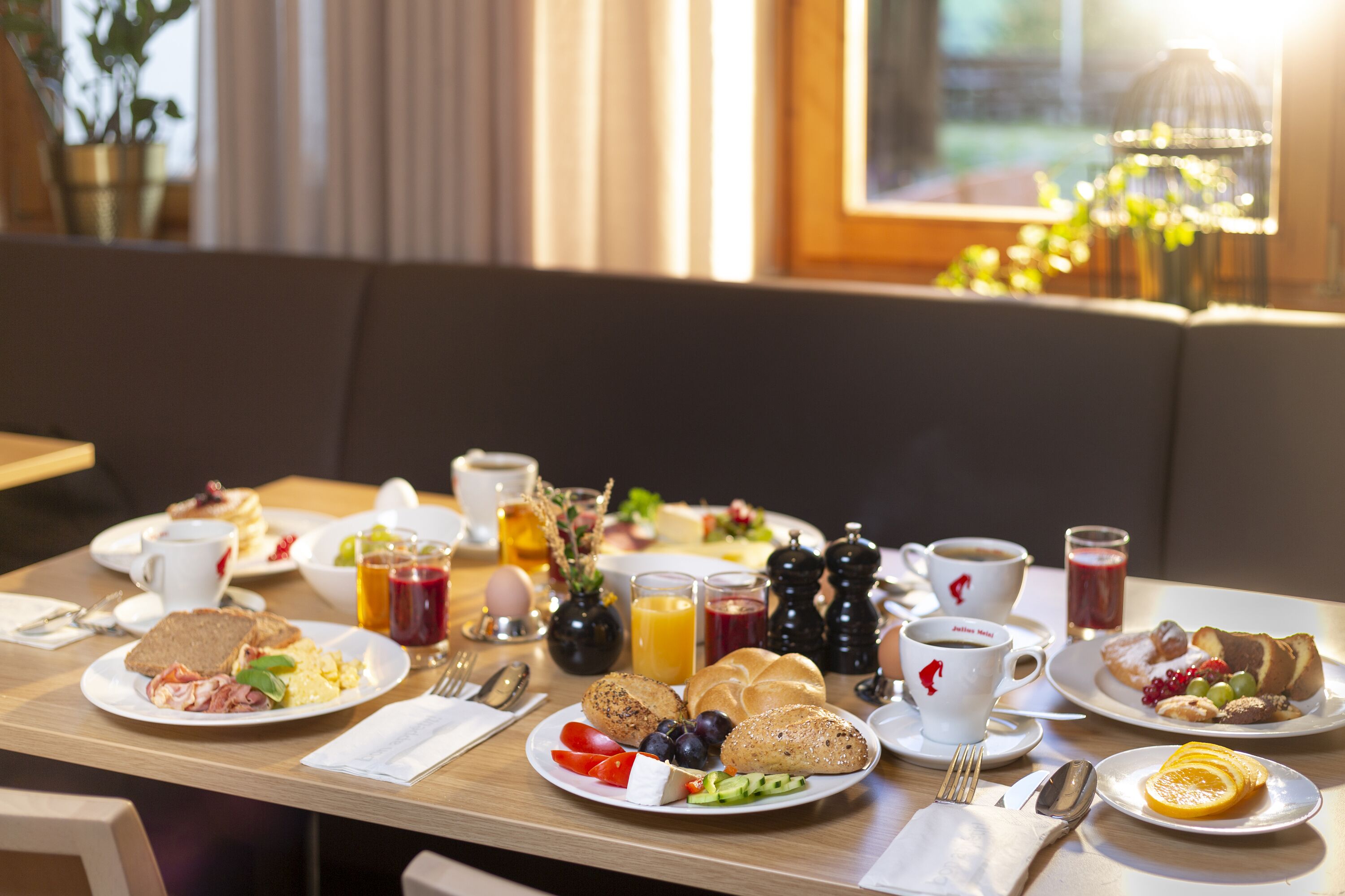 Una mesa de desayuno con diversos platos, tazas y cubiertos.
