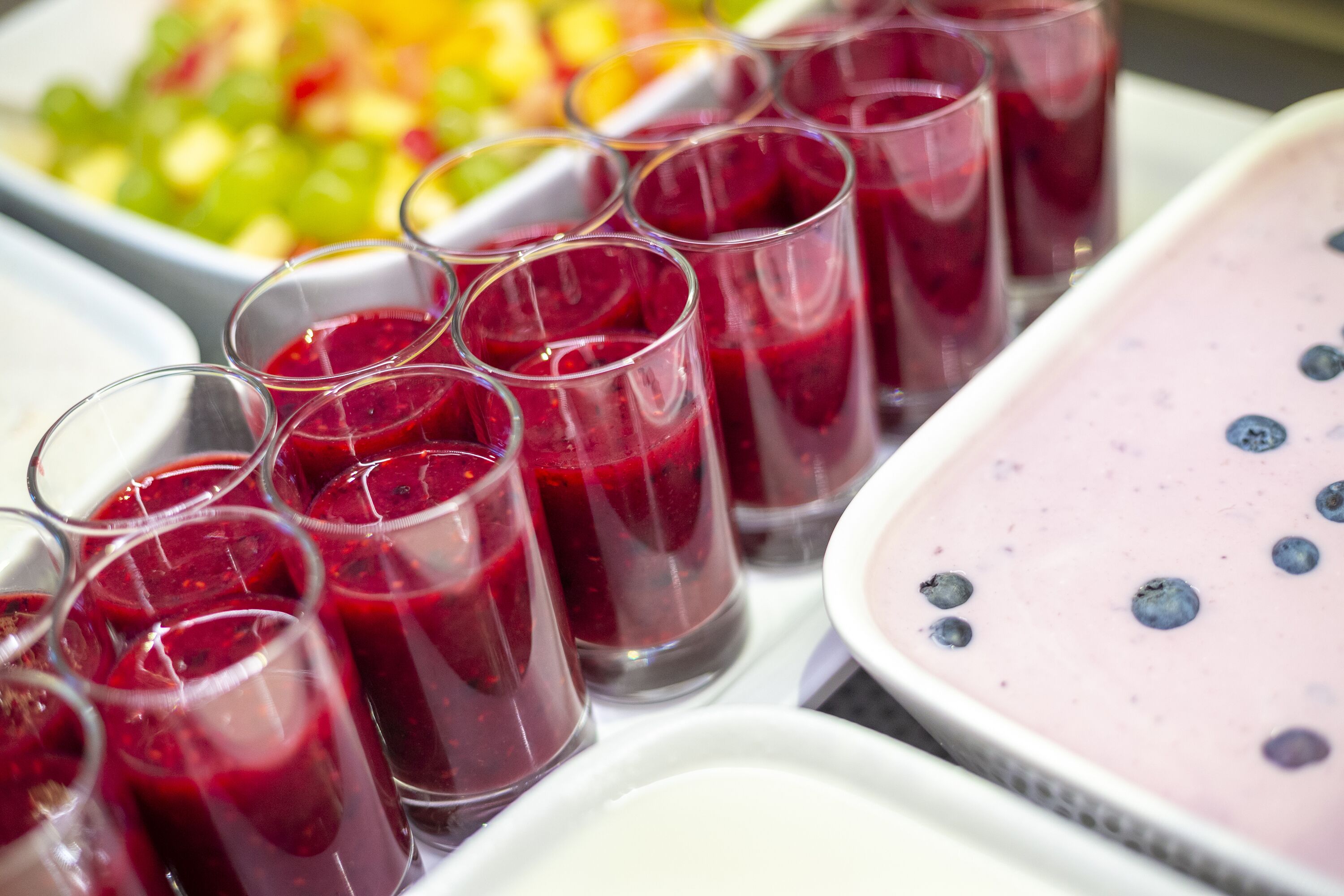 A variety of beverages, including red and blueberry drinks, served in glasses and a dish.