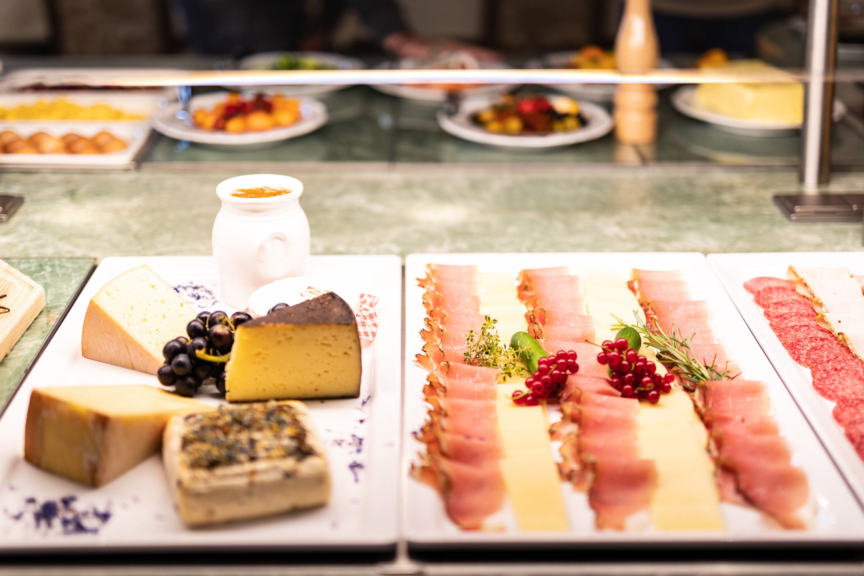 A cheese and charcuterie board with various cheeses, meats, and garnishes.