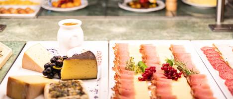 A cheese and charcuterie board with various cheeses, meats, and garnishes.