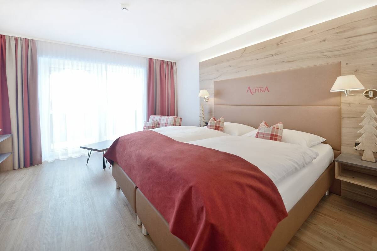 A hotel room with a large bed, a desk, and a nightstand.