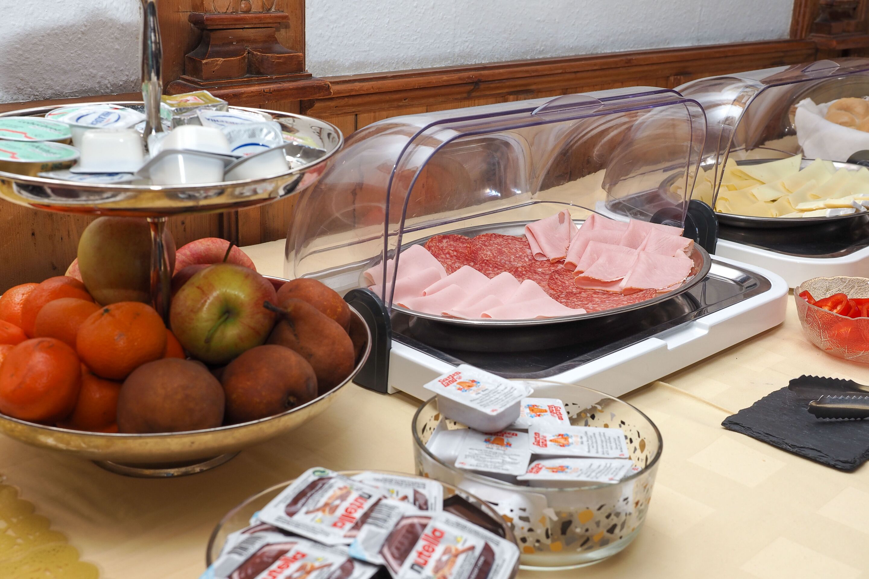 Un bufé con diversos alimentos, incluyendo frutas, carnes y aperitivos empaquetados.