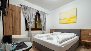 A neatly arranged hotel room with a bed, a table with a coffee maker, and a painting on the wall.