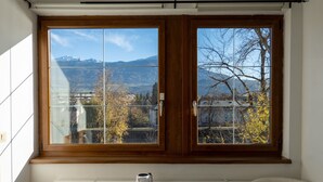 Una habitación con un amplio ventanal que ofrece vistas a montañas y árboles.
