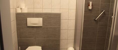 Un baño moderno con inodoro, ducha y un dispensador de papel higiénico.