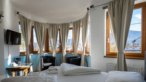 Una habitación de hotel con una cama, dos sillas, una mesa con cafetera y un televisor.
