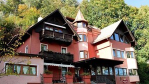 Un hotel de varios pisos con fachada roja, balcones y un letrero que indica 'HOTEL - ROOMS'.
