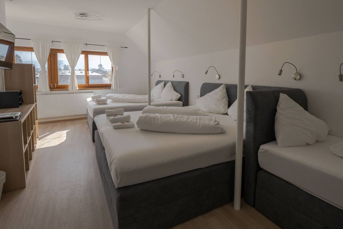 A hotel room with two beds, a desk, and a view of the outside.