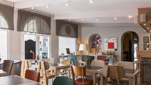 L'intérieur d'un restaurant moderne, avec de nombreuses tables et chaises, un bar et une vue sur la rue.