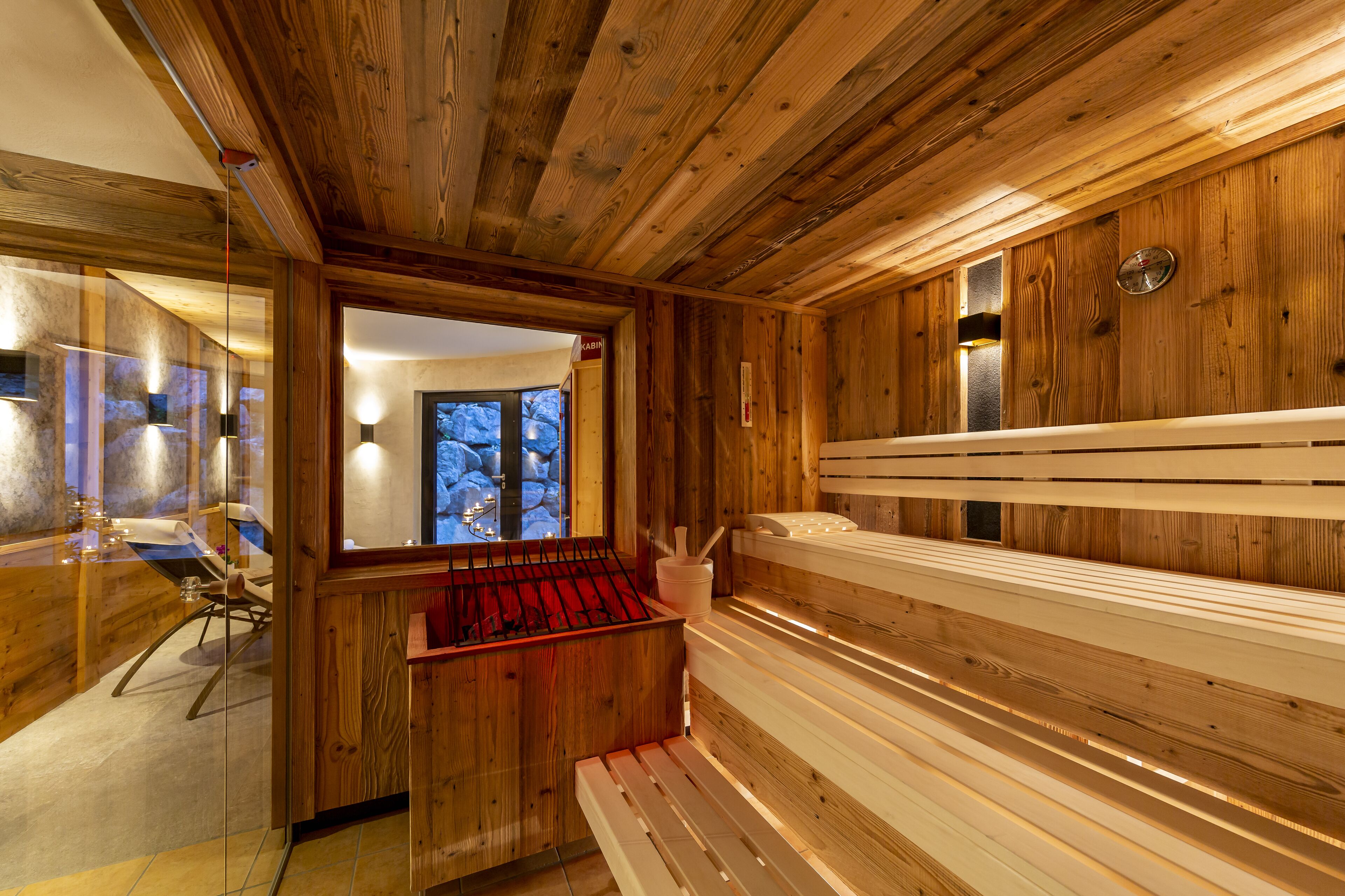 A wooden cabin interior with a sauna, a glass-walled shower area, and a wooden bench.