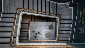 A modern interior with a unique geometric floor plan, wooden panel walls, and a central seating area with plants. - Azur (Marseille)