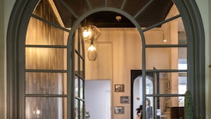 A cozy interior with a wooden floor, a floral armchair, a cactus, and a dining area with chairs and a table. - Azur (Marseille)