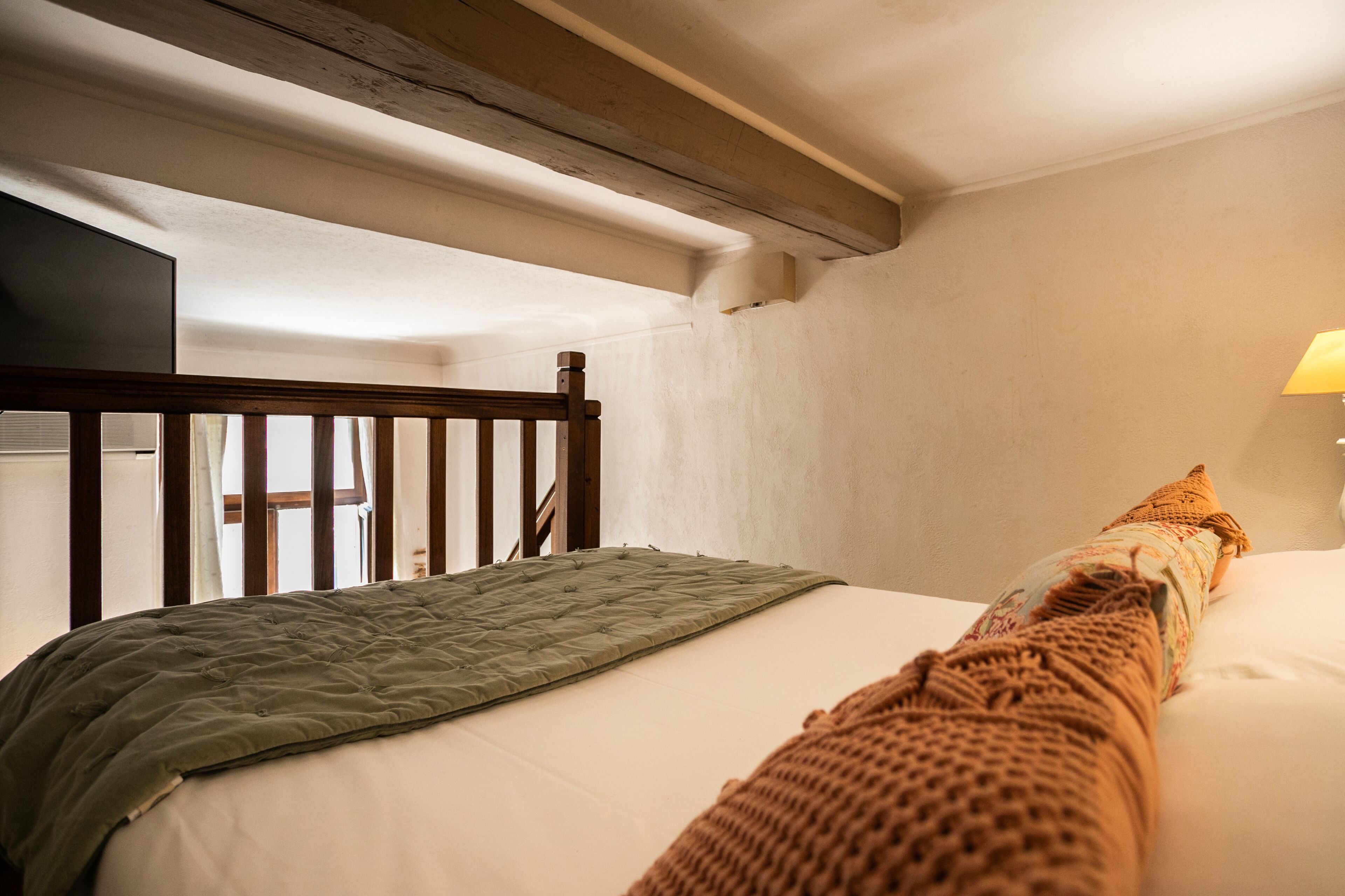 Un dormitorio con cabecera de madera, colcha verde acolchada y almohada blanca.