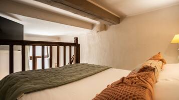 A bedroom with a wooden headboard, a green quilted bedspread, and a white pillow.