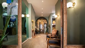 A hallway with a wooden chair, a mirror, and a reception desk. - Azur (Marseille)