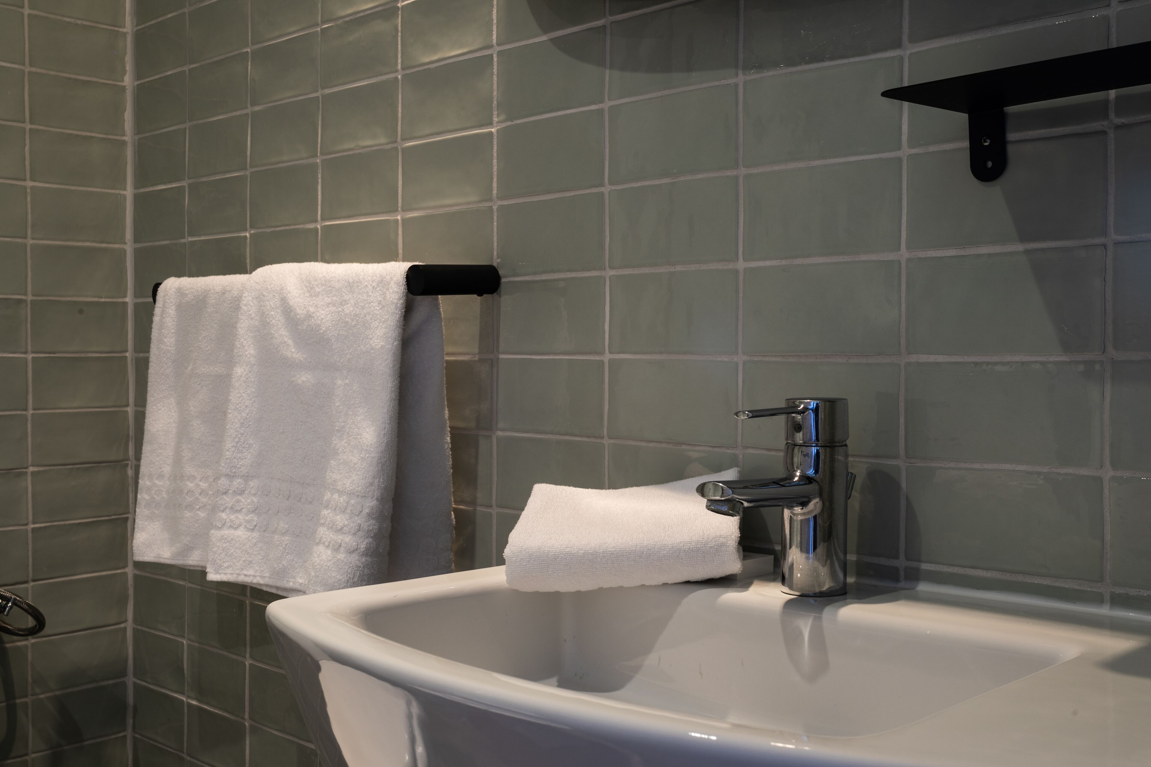 Une salle de bain avec un lavabo blanc, une serviette suspendue à un porte-serviettes et un support à papier toilette.