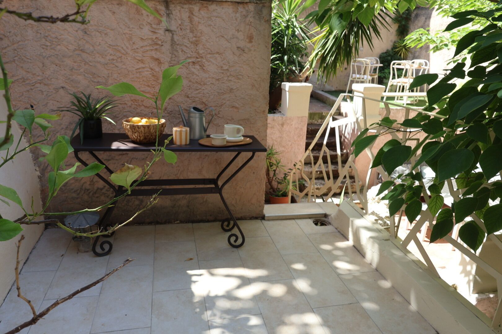 A patio area with a metal table, potted plants, and outdoor furniture.