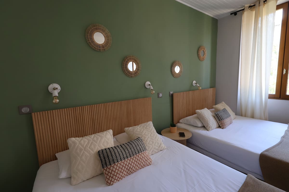 A hotel room with two beds, green walls, and decorative mirrors.