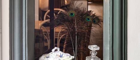 An arched doorway leading to a room with a decorative peacock feather and a crystal decanter on the floor.