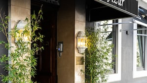 The exterior of Hotel Azur with a black awning, a set of steps leading to the entrance, and two potted plants on either side. - Azur (Marseille)