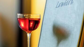 Um copo de vinho tinto ao lado de uma superfície metálica com texto gravado.