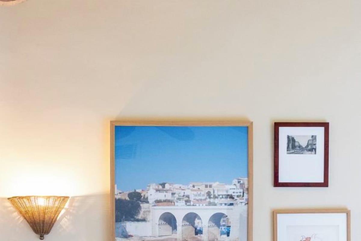 Una fotografía enmarco de un puente, una lámpara fijada a la pared y un cuadro colgado en la pared.