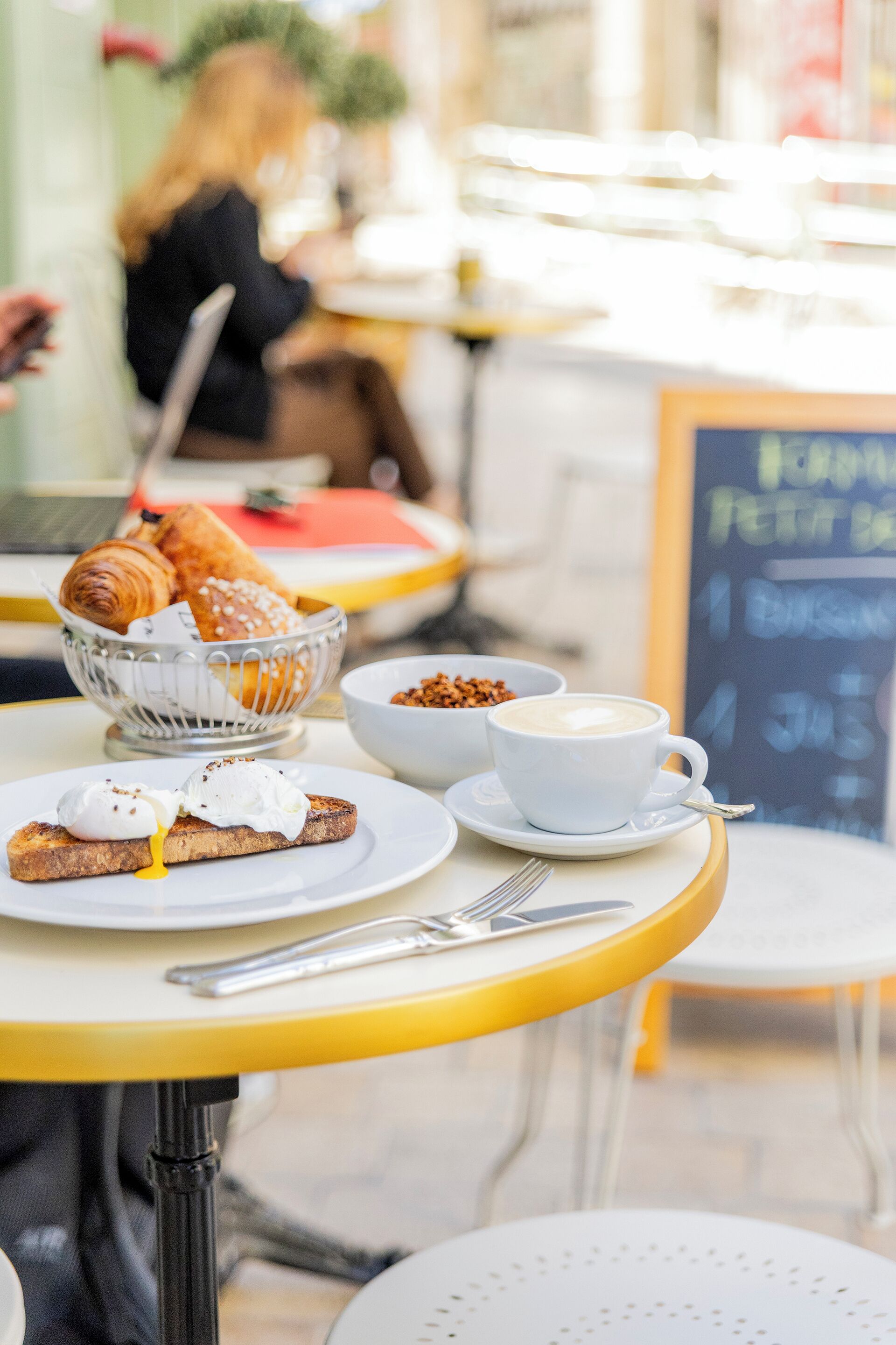 A café table with croissants, coffee, and a bowl of nuts.