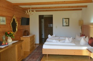 A wooden-paneled room with a bed, dresser, and a television on the wall. - Sporthotel Zugspitze (Lermoos)