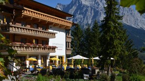 A hotel with outdoor seating, a mountain backdrop, and a sign reading "SPORTHOTEL SPITZE Restaurant". - Sporthotel Zugspitze (Lermoos)