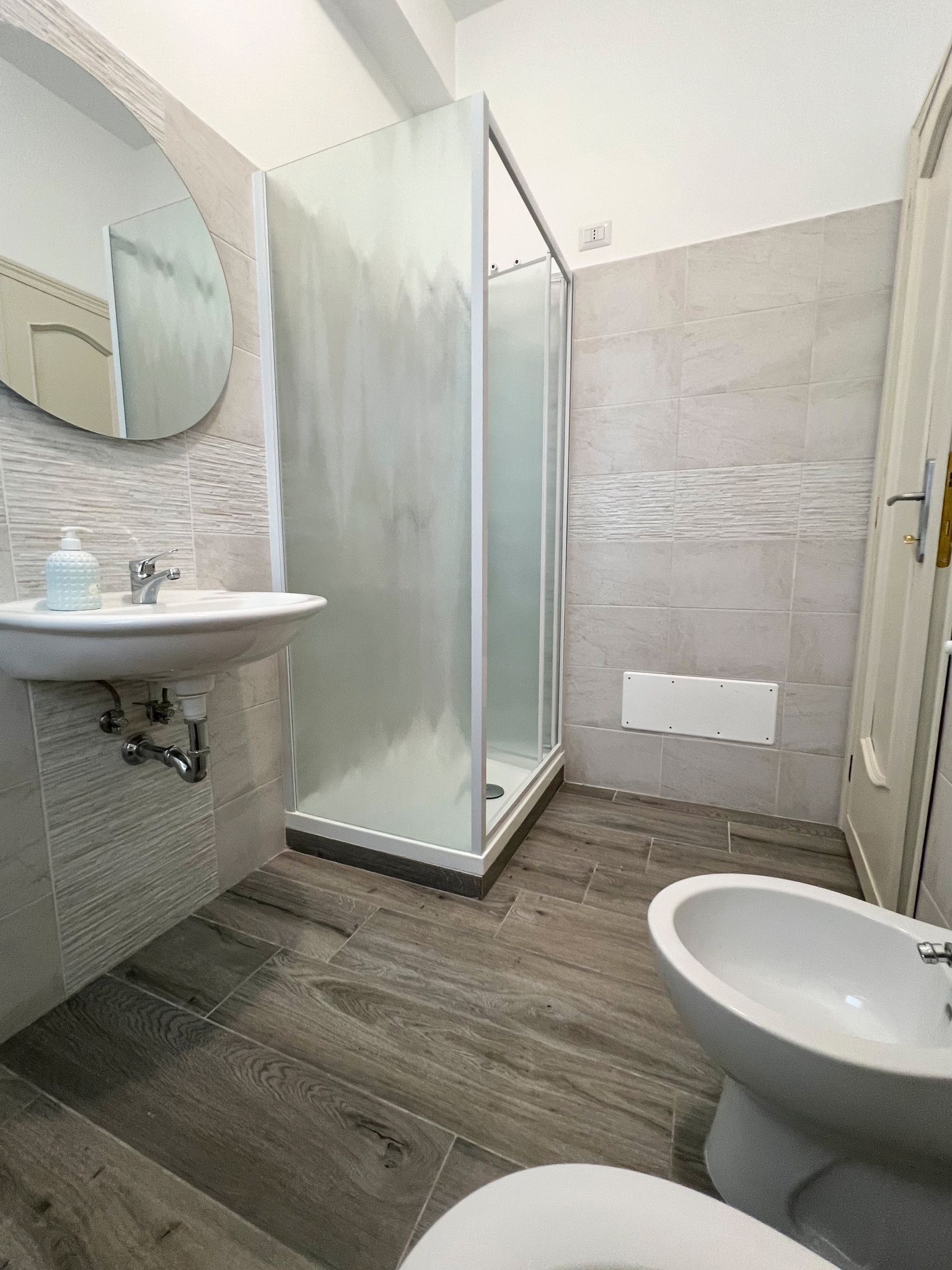 A modern bathroom with a glass shower enclosure, a sink, and a bidet.
