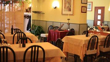 Ein Restaurant mit mehreren Tischen und Stühlen, einem dekorativen Raumteiler und Wandleuchten.