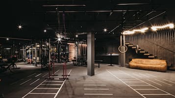 A gym with weightlifting equipment, a staircase, and a sofa.