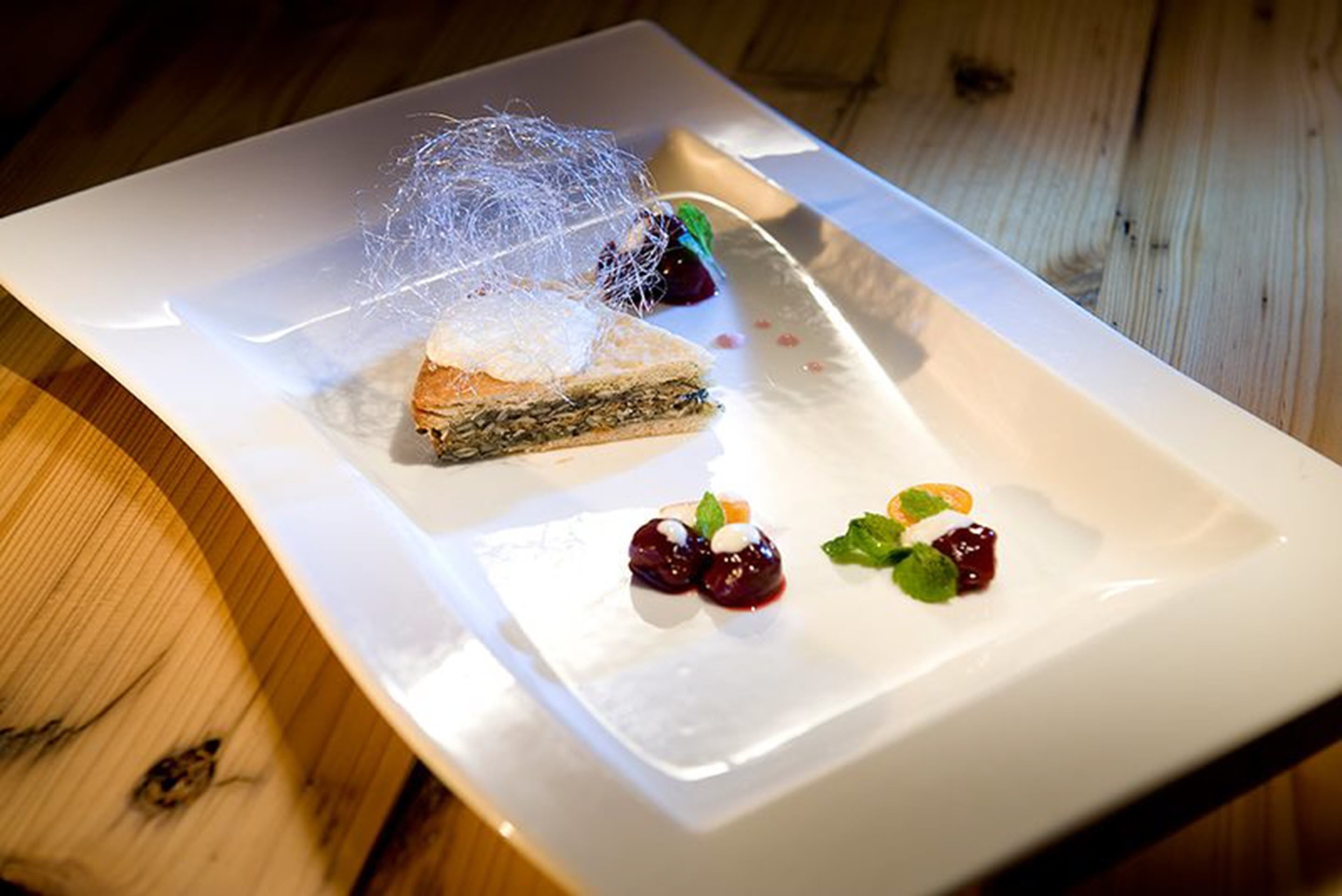 A dessert plate with a slice of cake, berries, and a decorative element on a white plate.