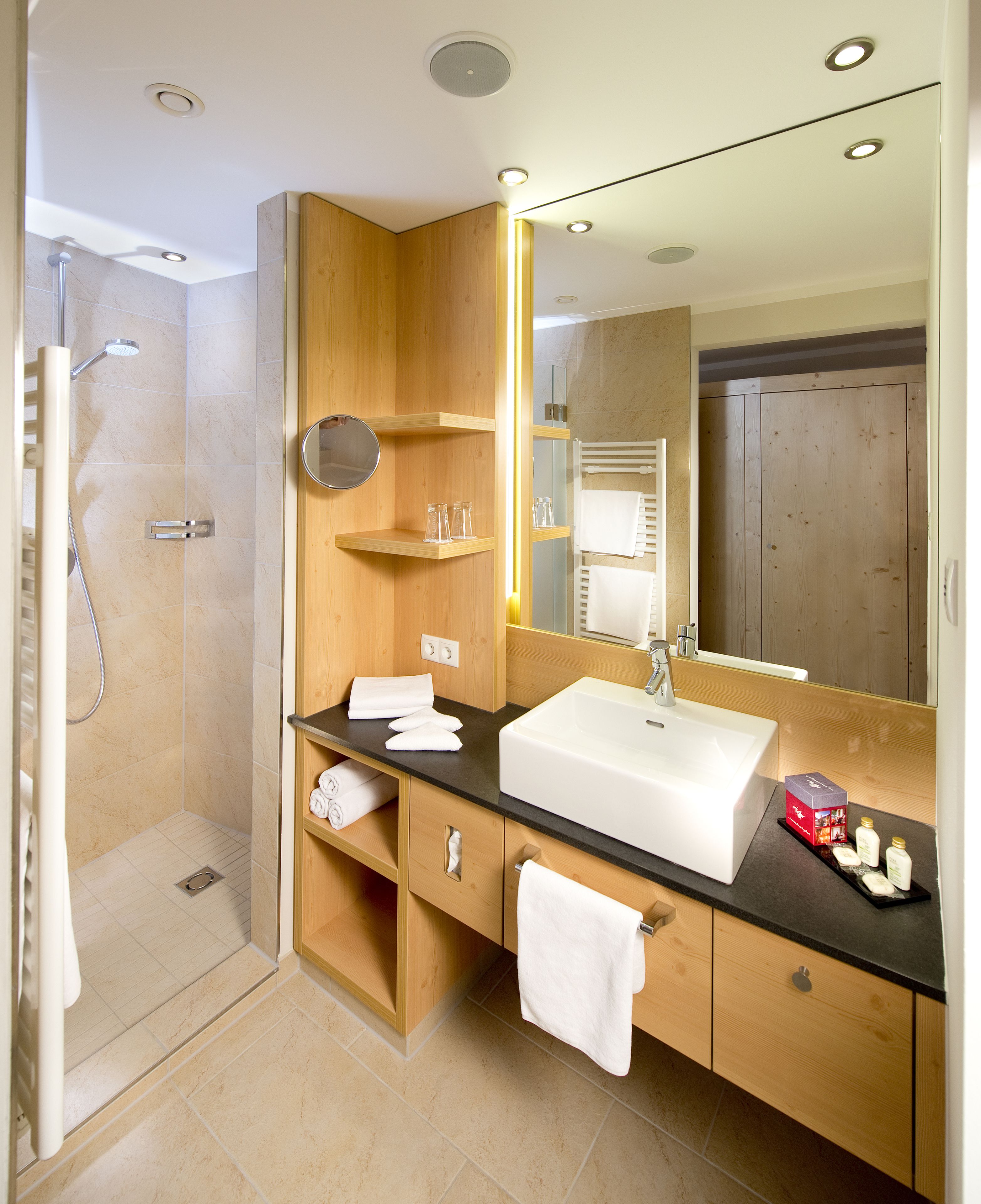A modern bathroom with a shower, sink, and wooden cabinets.