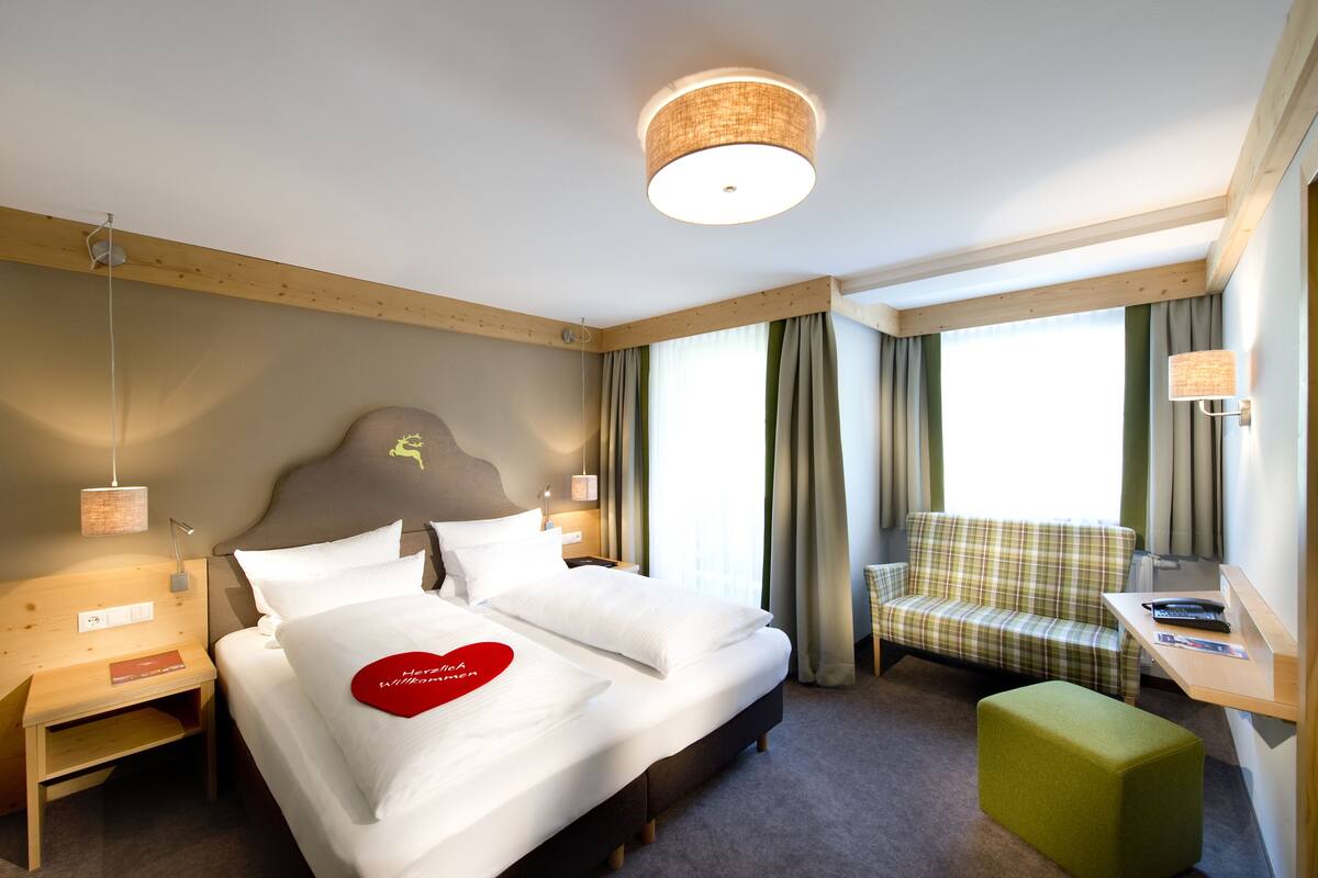 Una habitación de hotel con cama, escritorio, silla y sofá.