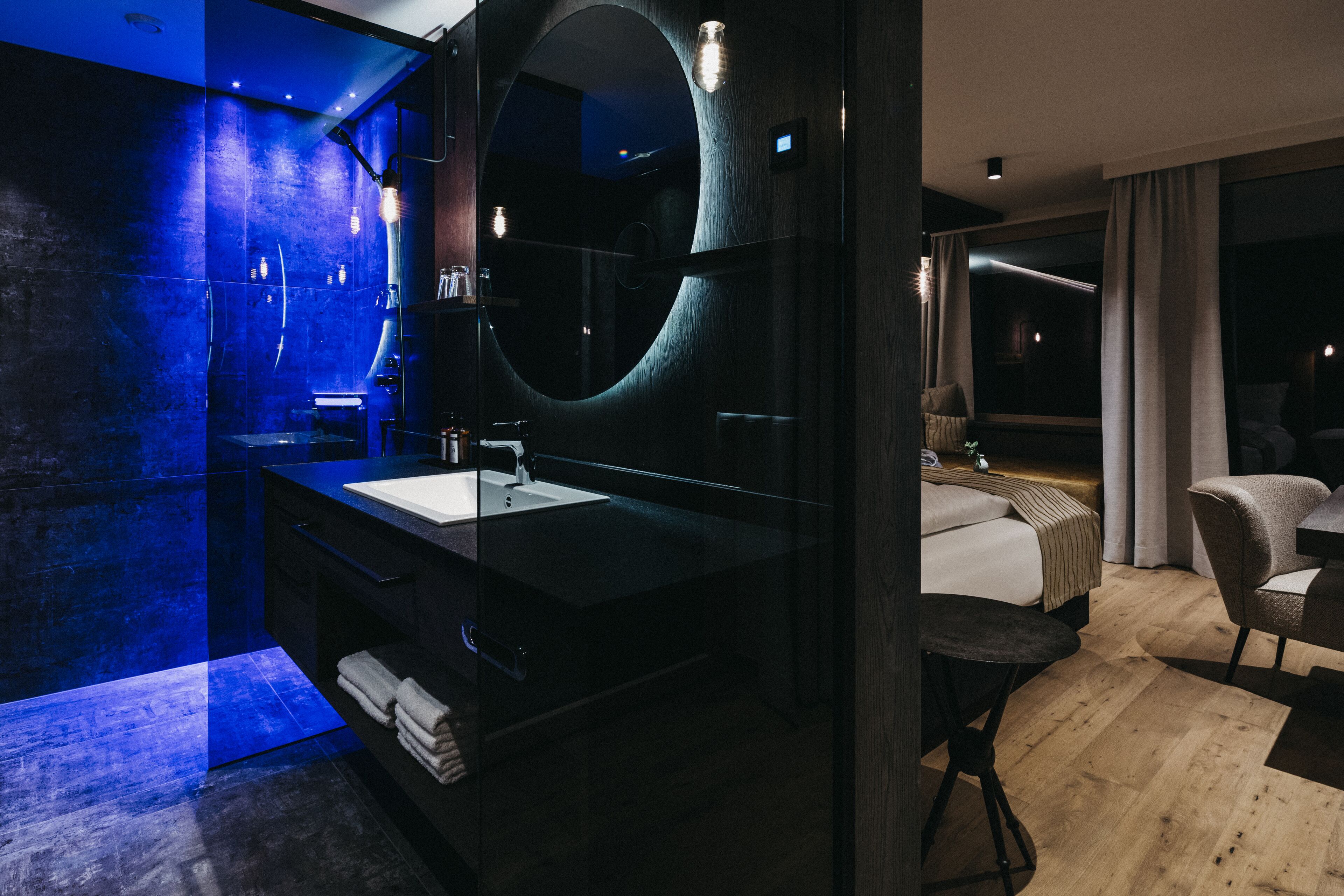 Un baño moderno con un espejo grande, tocador negro y lavamanos.