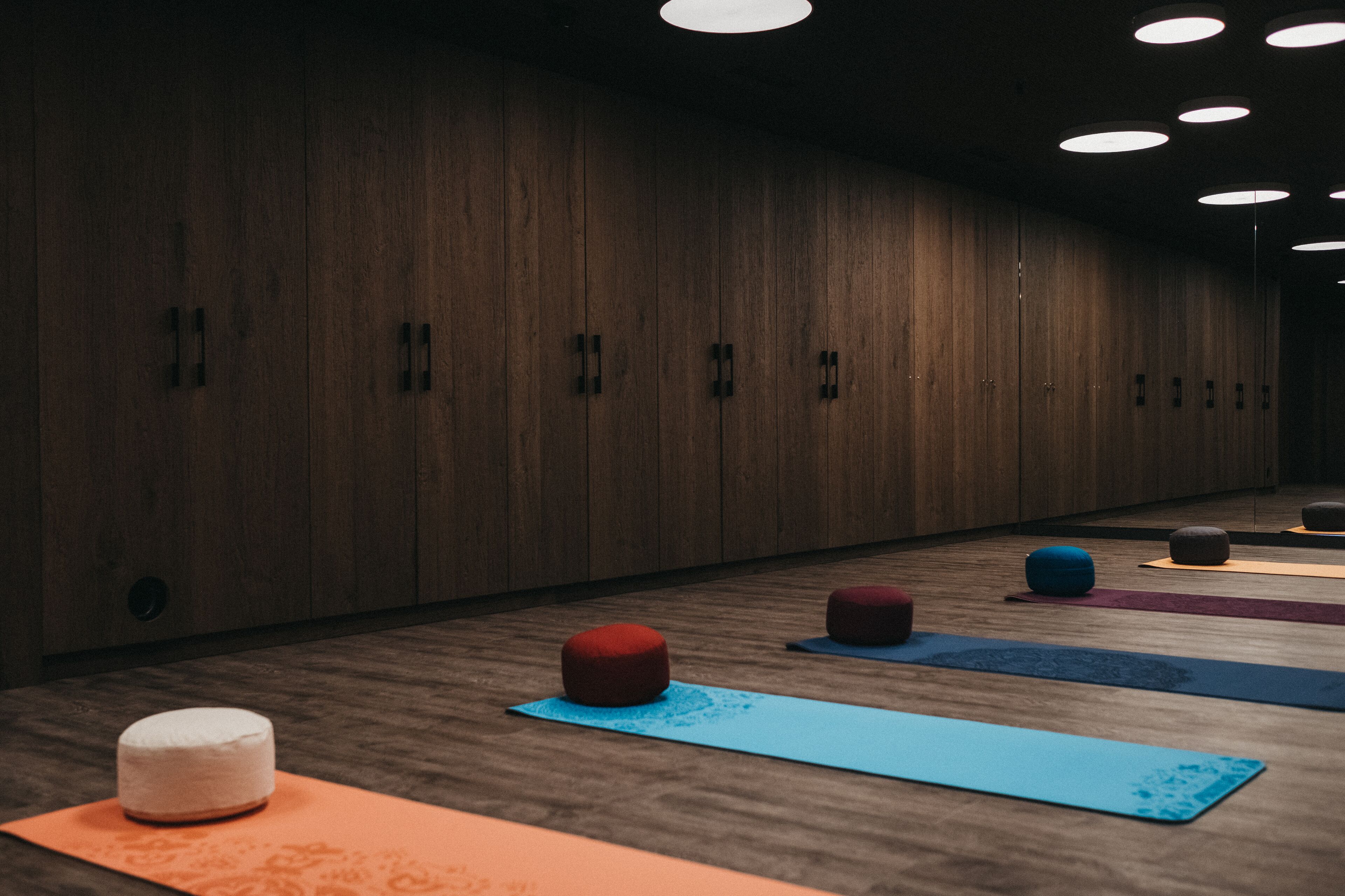A yoga studio with wooden walls, multiple yoga mats, and small stools.