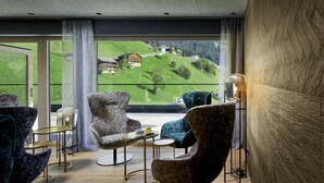 A modern living room with a view of a green hillside. - Hotel Tirolerhof (Tux)