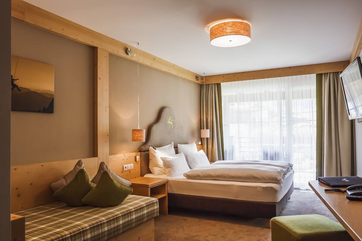 Una habitación de hotel con una cama grande, un escritorio, una silla y un televisor.
