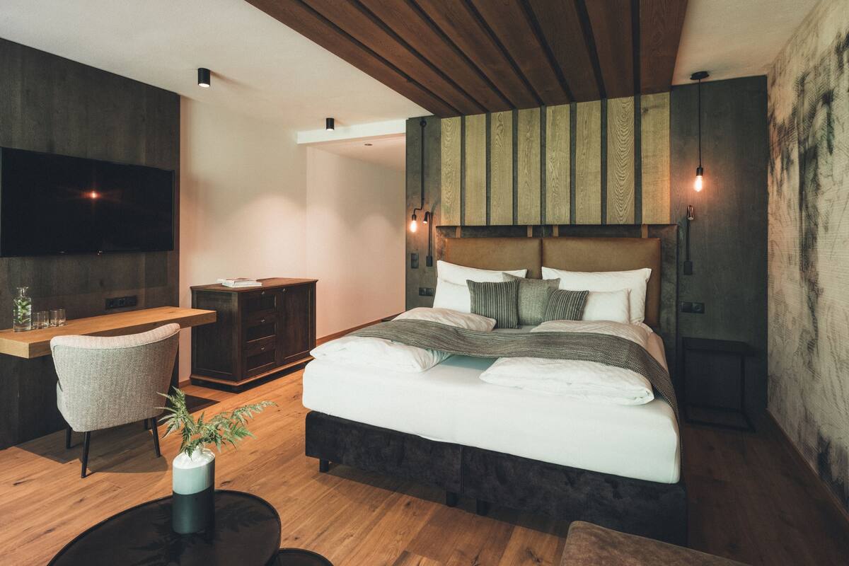 Un dormitorio moderno con una cama grande, un escritorio y un televisor.