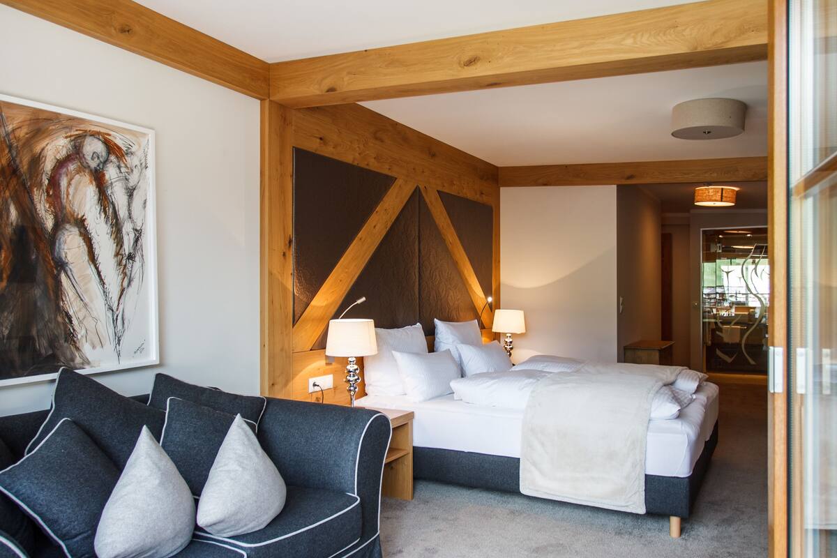 Una habitación de hotel moderna con una cama grande, un escritorio y una silla. Hay un cuadro en la pared y una ventana con vistas al exterior.