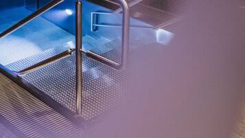 A steam room with a glass enclosure and metal railings.