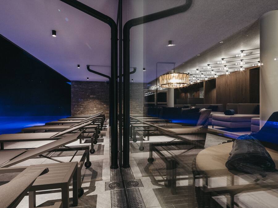 A modern lounge area with seating arrangements, a large chandelier, and a stone wall.